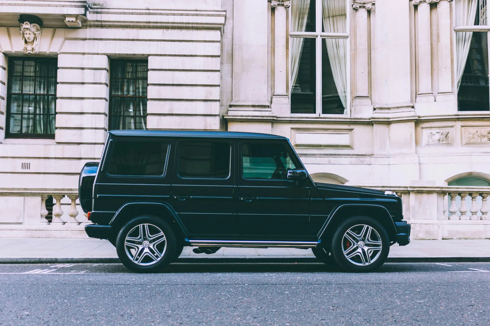 A black four-wheel-drive parked beside a white stucco building